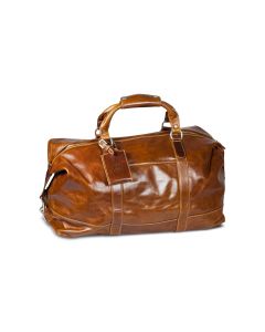 Front view of this captain's bag. It features British tan Florentine leather. It has a strap attached and a luggage tag. The luggage tag has initials placed on it.